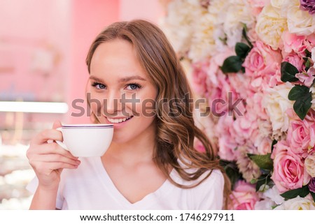 Beautiful smiling woman drinking coffee at cafe. Portrait of mature woman in a cafeteria drinking hot tea and looking at camera. Pretty woman with cup of coffee.
