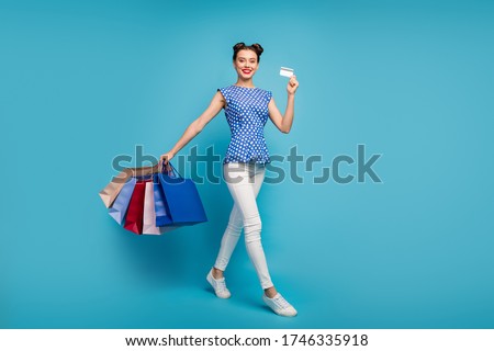 Full body profile photo of pretty funny lady walk street carry many packs plastic credit card addicted shopper wear dotted retro blouse white pants footwear isolated blue color background
