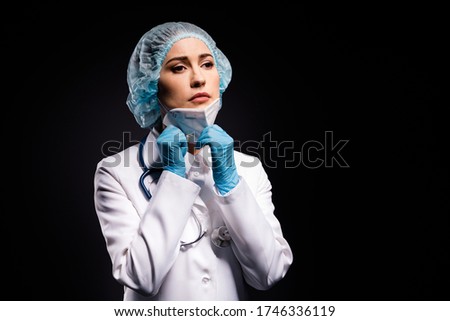 Photo of tired lady doc taking off protective mask after late operation breathing fresh air dream come home wear gloves lab white coat surgical cap isolated black color background