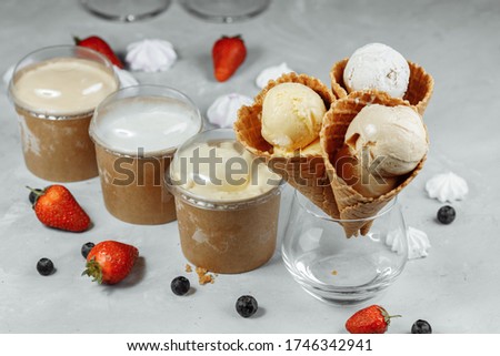 ice cream in a waffle cone on a light background. The ice cream is melting. Waffle cones and strawberries in the background.