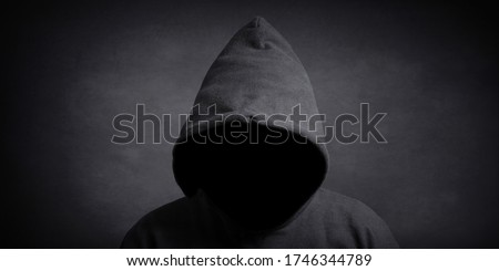 faceless person wearing black hoodie hiding face in shadow - mystery crime conspiracy concept Royalty-Free Stock Photo #1746344789