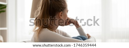 Girl sit on couch looking in distance out the window feels frustrated. Break up with boyfriend, personal life problems, unwilling pregnancy concept. Horizontal photo banner for website header design Royalty-Free Stock Photo #1746359444