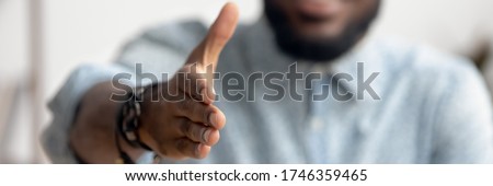 Close up African agent reach out hand to camera handshake client. Make deal, company boss HR recruiter greet applicant starting job interview concept. Horizontal photo banner for website header design