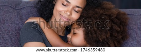 Horizontal photo banner for website header design close up african mom hug little daughter sit on sofa enjoy moment of sweet embracing showing love care, parental protection, motherhood, unity concept Royalty-Free Stock Photo #1746359480