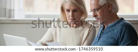 60s spouses serious couple read financial statement papers analyzing family expenses feels concerned. Bank debt, overspend, finance problems concept. Horizontal photo banner for website header design