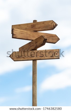 Wooden sign post isolated on blue sky with white clouds. Direction concept. Mock up, template