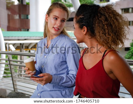 Two young business woman smile talking and relaxation in free time at walking street.