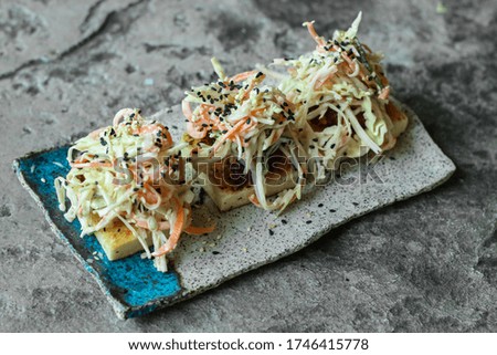 Delicious appetizer served on creative plate on texture background. Fresh toast with grilled meat, mixed cutting vegetables and black sesame seeds. Image