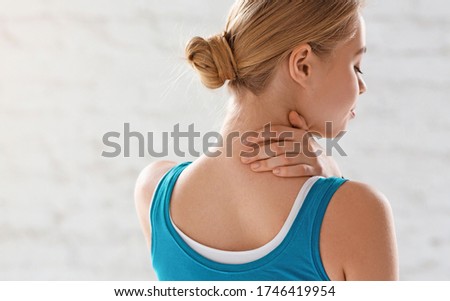 Sports injury concept. Athletic girl feeling pain in her neck against white background, copy space