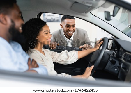 Car Sales.  Couple Choosing New Vehicle Talking With Dealer Sitting In Auto In Dealership Shop. Selective Focus Royalty-Free Stock Photo #1746422435