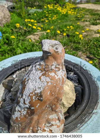 gypsum figure in the form of a bird in a summer cottage on a background of grass and yellow dandelions