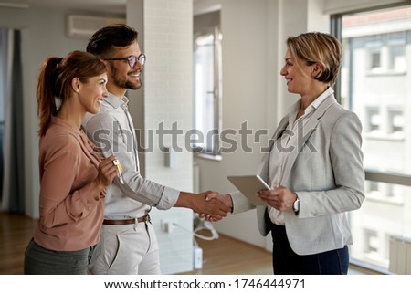 Happy real estate agent and young couple shaking hands after successful agreement.  Royalty-Free Stock Photo #1746444971