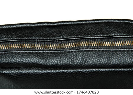 Zipper golden color on the black leather bag, close up photo. Leather texture black. On white background.