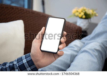 male hand holding phone with isolated screen at home in the room
