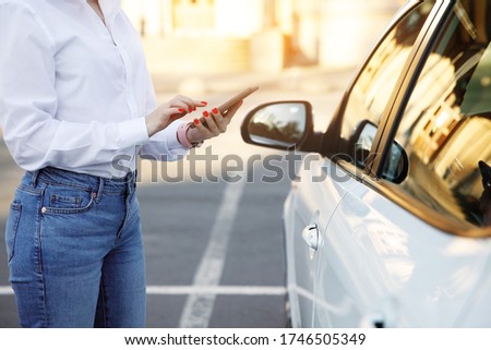 Close up woman using mobile phone, communication or online application, standing near car on city street or parking, outdoors. Car sharing, rental service or taxi app.  Royalty-Free Stock Photo #1746505349