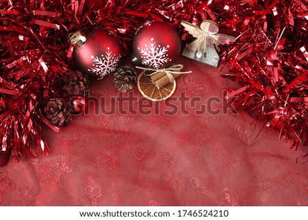 red Christmas balls, cones, dried slice of orange on a red background                              