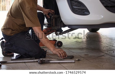 Man mechanic technician worker installing car wheel maintenance in auto service. Hand of mechanic man repair disk brake and car disk brake system service. Selective focus.