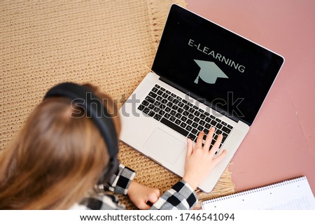 Distance education concept. Happy schoolgirl with laptop on the floor doing homework. Distance home schooling. Online education