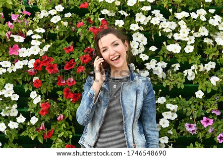 Girl emotionally talking on the phone, against the background of flowers