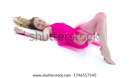 A cute girl gymnast of school age is lying on the floor with lon