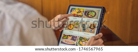 man orders food for lunch online using Tablet BANNER, LONG FORMAT Royalty-Free Stock Photo #1746567965