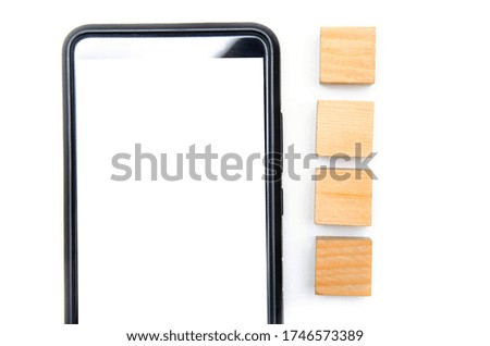Wooden cubes and smartphone on a white background. The smartphone lies to its right four cubes directly and at an angle the smartphone in the macro white screen of the smartphone