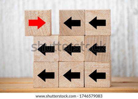 Wood cube presents red arrow facing opposite direction, Concept of think different, leadership mindset, people management and standing out from the crowd
