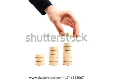 development concept on white background. man's hand builds a tower of toy wooden round blocks on a white background