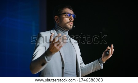 Great Motivational Speaker Stands on Stage, Talks about Happiness, Self, Success, Technology and How To Be Productive. Startup Presenter Pitching Ideas. Cinematographic Photo. Royalty-Free Stock Photo #1746588983