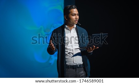 Business Conference Stage: Indian Tech Development Guru Presents Firm's Newest Product, He's Holding Laptop and Does Motivational Talk about Science, Technology, Software Development and Leadership Royalty-Free Stock Photo #1746589001