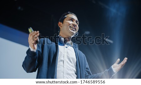 Portrait of Visionary Speaker Presenting New Product, Shows Infographics, Statistics Animation on Screen, Talks About Device Performance. Live Event  Device Release  Start-up Conference. Low Angle Royalty-Free Stock Photo #1746589556