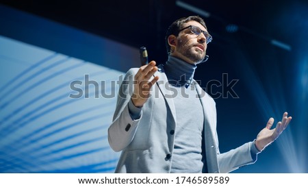 Portrait of Inspirational Innovative Speaker, Talking about Happiness, Self, Success, Empowerment, Efficiency and How to Be More Productive Self. Large Conference Hall with Cinematographic Light Royalty-Free Stock Photo #1746589589