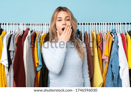 Teenager Russian girl buying some clothes isolated on blue background yawning