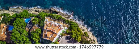 Panoramic view directly from above coast and Mediterranean Sea. Summer luxury villas with swimming pools, parking area, sport tennis field. Mallorca or Majorca Island, Balearic Islands, España, Spain
