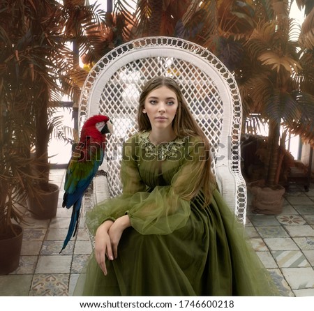 Art photo gravel of a graceful long-haired girl in a chair with a red macaw parrot