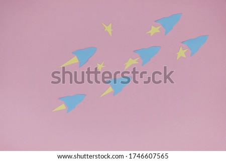 Paper blue space rockets fly between the stars on a pink paper surface. Space concept. Copy space.