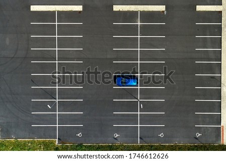 Top view on an empty parking lots with one blue car. Aerial view of car park. Royalty-Free Stock Photo #1746612626
