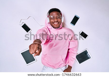 Young african-american man using devices, gadgets isolated on white studio background. Concept of modern technologies, gadgets, tech, emotions, ad. Gaming, shopping, meeting online Royalty-Free Stock Photo #1746632663