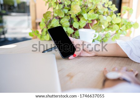 Young Caucasian girl's hand holds a smart phone with black screen.Copy space