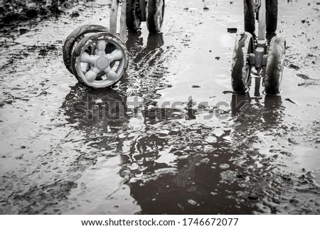 A road without a hard surface in rainy weather and wheels from a pram. Black and white image.