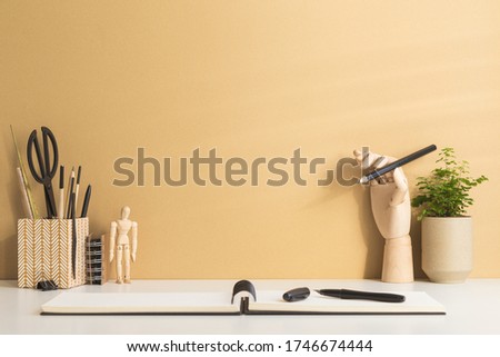 Workspace with notebok opened and brown wall. Creative desk with wooden supplies. Mockup.
