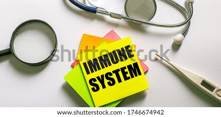 Immune system - written on a light background on bright paper near a stethoscope, magnifier and an electric thermometer 