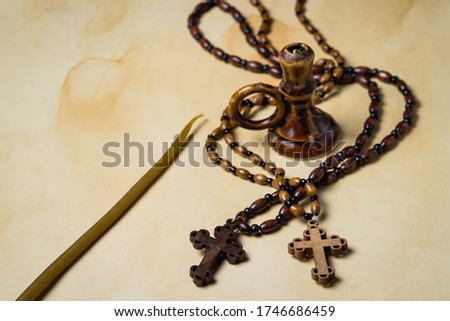Religion concept. Christian religion. Two wooden crosses on wooden chains. Between the crosses is a candlestick, next to it is a candle. Crosses lies on a background of old paper. photo on top