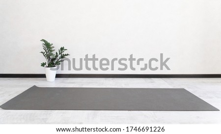 Empty white space in the fitness center, light walls, natural floor, modern loft Studio, unfolded yoga Mat on the floor, comfortable outdoor area for sports and exercise