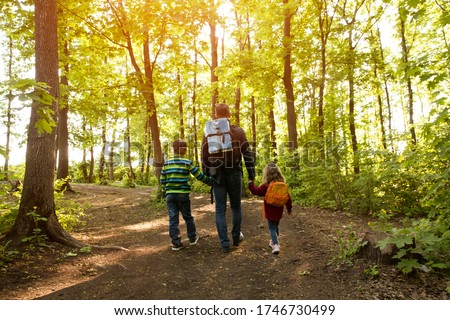 father and two kids with backpack hiking in forest. Social Distancing. Digital detox. Staycations, hyper-local travel,  family outing, getaway, natural environment Royalty-Free Stock Photo #1746730499