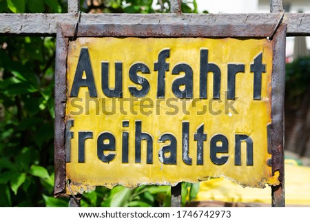 A weathered, rusty, yellow colored sign with the words "Einfahrt freihalten", translation: keep gateway clear, in black letters. 