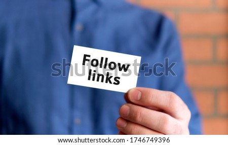 A man in a blue shirt holds a sign with the text of Follow links in one hand