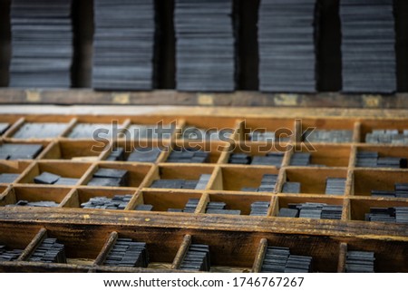 Printing press letter blocks in a wooden shelf.