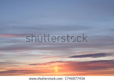 Evening sky at sunset in purple, orange and light gray tones. Beautiful sunset with Cirrus clouds. Summer sky at sunset, cirrocumulus