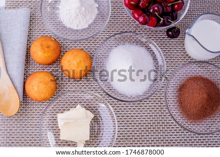 Ingredients for making homemade cupcakes with chocolate and cherries. Classic recipe for making dessert at home.